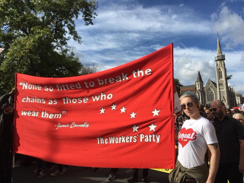 Marchers carrying a red Workers' Party banner with a quotation attributed to James Connolly